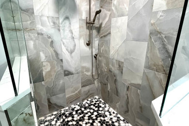 Modelo de cuarto de baño principal actual de tamaño medio con ducha esquinera, paredes grises, suelo de baldosas tipo guijarro y ducha con puerta con bisagras