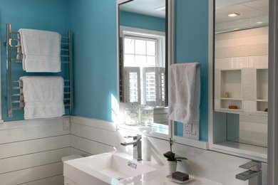 ニューヨークにある広いシャビーシック調のおしゃれなマスターバスルーム (フラットパネル扉のキャビネット、白いキャビネット、大型浴槽、シャワー付き浴槽	、分離型トイレ、青い壁、一体型シンク、シャワーカーテン、白い洗面カウンター、洗面台2つ、造り付け洗面台) の写真
