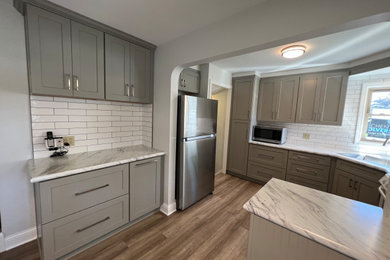 Example of a mid-sized classic u-shaped vinyl floor eat-in kitchen design in Cleveland with gray cabinets, laminate countertops, white backsplash and subway tile backsplash