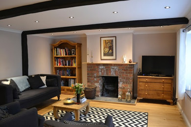 Inspiration for an eclectic living room in Oxfordshire with medium hardwood floors and a brick fireplace surround.