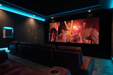 Photo of a large modern home cinema in Sussex with grey walls, carpet, a projector screen and grey floors.
