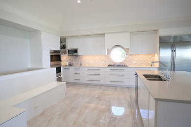 Large minimalist single-wall porcelain tile and white floor eat-in kitchen photo in Toronto with a double-bowl sink, flat-panel cabinets, white cabinets, quartzite countertops, white backsplash, mosaic tile backsplash, stainless steel appliances, an island and white countertops