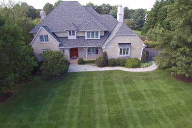 Example of a large classic beige two-story brick exterior home design in DC Metro with a tile roof