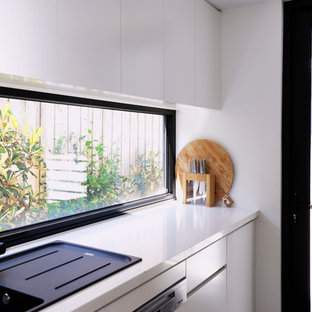 Large contemporary kitchen pantry ideas - Large trendy galley concrete floor and gray floor kitchen pantry photo in Geelong with white cabinets, quartz countertops, window backsplash, stainless steel appliances and an island