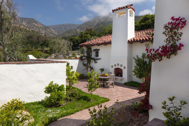 Inspiration for a medium sized mediterranean courtyard patio in Santa Barbara with a fireplace and no cover.