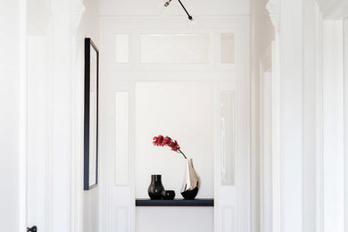 This is an example of a traditional hallway in Sydney with white walls and light hardwood floors.