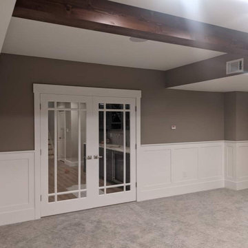 Basement with a banquette, beams, wainscot and bookcases