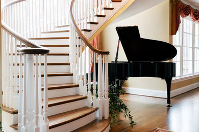 Photo of a large traditional wood curved staircase in Raleigh with wood risers.