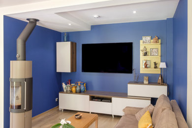 Idée de décoration pour un salon blanc et bois minimaliste de taille moyenne et ouvert avec un mur bleu, parquet clair, un poêle à bois, un téléviseur fixé au mur et un sol marron.