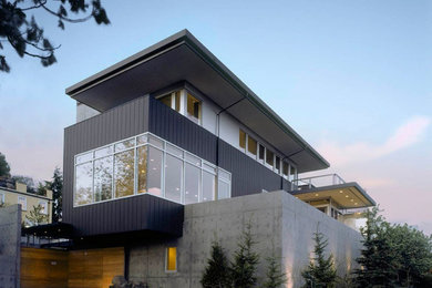 Foto de fachada de casa gris y gris actual grande de tres plantas con revestimientos combinados, tejado plano, tejado de metal y tablilla