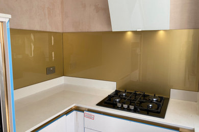 Photo of a contemporary kitchen in Manchester with metallic splashback and glass sheet splashback.
