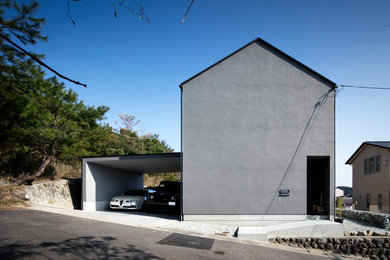 Small modern two-storey grey house exterior in Kobe with a gable roof and a metal roof.