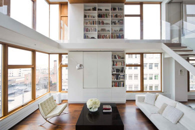 Example of a large minimalist loft-style medium tone wood floor and brown floor living room design in New York with white walls