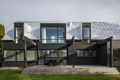 Inspiration för mellanstora moderna svarta hus, med två våningar, sadeltak och tak i metall