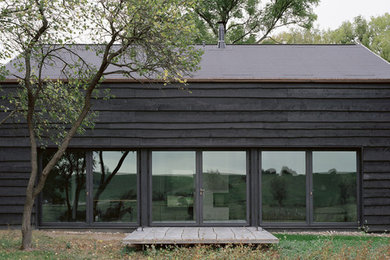 Inspiration for a small country one-storey black house exterior in Berlin with wood siding and a gable roof.