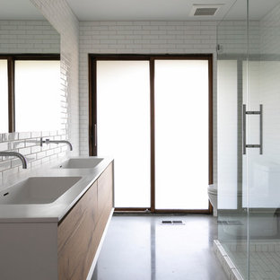 Esempio di una stanza da bagno moderna con ante lisce, ante in legno scuro, doccia ad angolo, piastrelle bianche, pareti gialle, pavimento in cemento, lavabo integrato, pavimento grigio, porta doccia a battente e top bianco