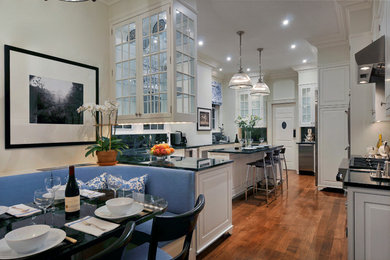 Kitchen - large traditional l-shaped medium tone wood floor kitchen idea in New York with an undermount sink, raised-panel cabinets, white cabinets, marble countertops, black backsplash, stone slab backsplash, stainless steel appliances and an island