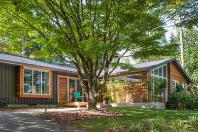 Photo of a mid-sized midcentury one-storey grey house exterior with a shingle roof.