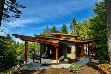 Example of a mid-sized trendy beige one-story concrete fiberboard and clapboard house exterior design in Seattle with a butterfly roof, a metal roof and a gray roof