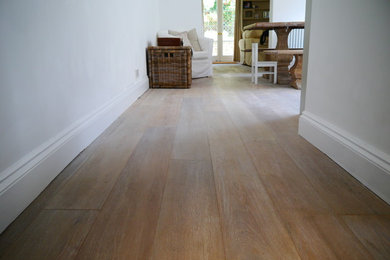 This is an example of a medium sized rustic l-shaped kitchen/diner in London with medium hardwood flooring, a belfast sink, shaker cabinets, green cabinets, composite countertops and no island.