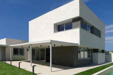 Modelo de fachada de casa blanca moderna de tamaño medio de dos plantas con revestimiento de piedra y tejado plano