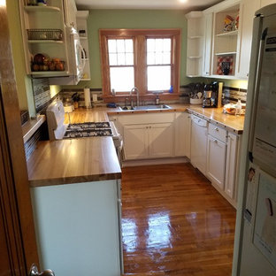 Small kitchen pantry ideas - Example of a small galley medium tone wood floor and brown floor kitchen pantry design in Jackson with a double-bowl sink, shaker cabinets, white cabinets, wood countertops, brown backsplash, glass tile backsplash, white appliances and no island