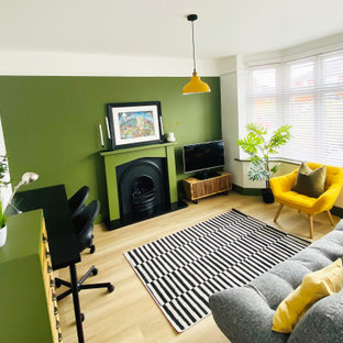 Mittelgroßes Modernes Arbeitszimmer mit grüner Wandfarbe, Vinylboden, Kaminumrandung aus Holz, freistehendem Schreibtisch und beigem Boden in Dorset