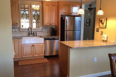 Small transitional l-shaped bamboo floor eat-in kitchen photo in Boston with a farmhouse sink, raised-panel cabinets, medium tone wood cabinets, quartzite countertops, beige backsplash, porcelain backsplash and stainless steel appliances