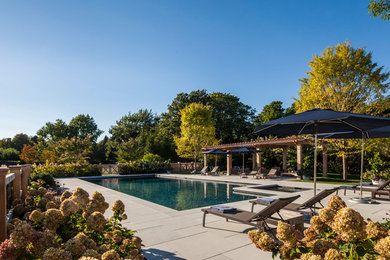 Inspiration for a mid-sized traditional backyard rectangular lap pool in New York with a pool house and natural stone pavers.