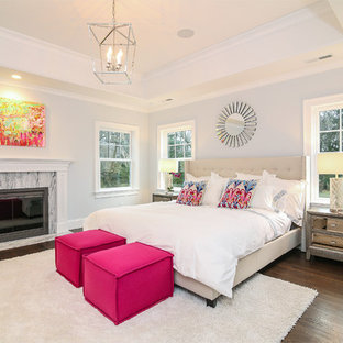 Foto på ett stort vintage huvudsovrum, med grå väggar, mörkt trägolv, en standard öppen spis och en spiselkrans i sten