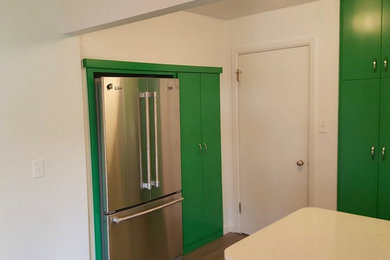 Example of a mid-sized eclectic medium tone wood floor kitchen design in Boise with flat-panel cabinets, green cabinets, white backsplash, subway tile backsplash, stainless steel appliances and an island