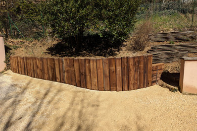 Diseño de jardín clásico de tamaño medio en patio delantero con muro de contención, gravilla y con madera