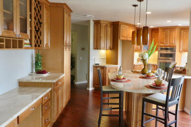 Mid-sized elegant u-shaped dark wood floor and brown floor eat-in kitchen photo in San Diego with an integrated sink, raised-panel cabinets, medium tone wood cabinets, marble countertops, white backsplash, ceramic backsplash, stainless steel appliances, an island and white countertops