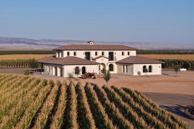 Example of a huge country white two-story stucco house exterior design in Other with a hip roof, a tile roof and a brown roof