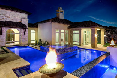 Large minimalist backyard stamped concrete and rectangular infinity hot tub photo in Austin