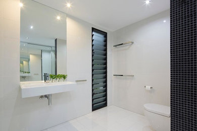 Mid-sized bathroom in Brisbane with a wall-mount toilet, white tile, porcelain tile and a wall-mount sink.
