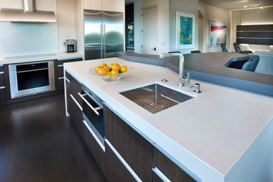 Large trendy u-shaped dark wood floor and brown floor eat-in kitchen photo in San Francisco with flat-panel cabinets, dark wood cabinets, quartz countertops, white backsplash, stainless steel appliances, two islands, white countertops, an undermount sink and glass tile backsplash