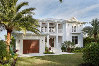Coastal white two-story house exterior idea in Miami with a hip roof and a metal roof