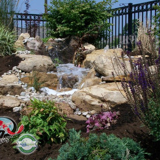 Großer Stilmix Garten hinter dem Haus mit Wasserspiel, direkter Sonneneinstrahlung und Mulch in Sonstige