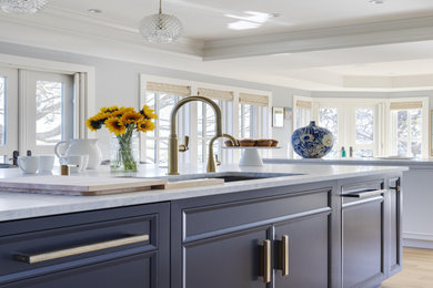 Huge beach style l-shaped light wood floor, brown floor and tray ceiling eat-in kitchen photo in Boston with an undermount sink, recessed-panel cabinets, blue cabinets, marble countertops, blue backsplash, marble backsplash, stainless steel appliances, two islands and blue countertops