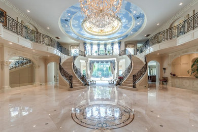 Example of a huge classic marble floor entryway design in Houston with beige walls and a glass front door