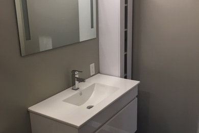 Esempio di una stanza da bagno padronale minimalista di medie dimensioni con ante lisce, ante bianche, WC a due pezzi, piastrelle grigie, pavimento in gres porcellanato, lavabo integrato, top in superficie solida, pavimento grigio e top bianco
