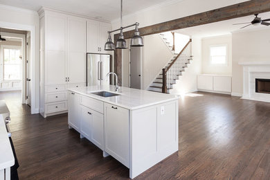 Photo of a large transitional single-wall separate kitchen in Atlanta with an undermount sink, shaker cabinets, beige cabinets, granite benchtops, white splashback, subway tile splashback, stainless steel appliances, dark hardwood floors, with island, brown floor and white benchtop.