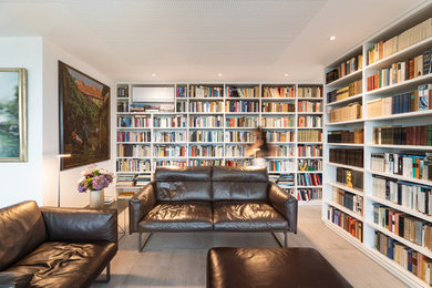 Imagen de sala de estar con biblioteca abierta actual pequeña con paredes blancas, suelo de baldosas de cerámica, televisor retractable, suelo gris y papel pintado