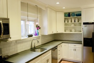 Example of a mid-sized transitional l-shaped light wood floor open concept kitchen design in Philadelphia with an undermount sink, shaker cabinets, white cabinets, concrete countertops, white backsplash, subway tile backsplash and stainless steel appliances