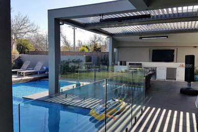 Inspiration for a large contemporary backyard patio in Melbourne with an outdoor kitchen, natural stone pavers and a pergola.