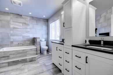 Bathroom - large contemporary master gray tile and porcelain tile porcelain tile and gray floor bathroom idea in Ottawa with white cabinets, a two-piece toilet, gray walls, an undermount sink, quartz countertops, a hinged shower door, black countertops and shaker cabinets