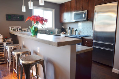 Mid-sized elegant u-shaped dark wood floor and brown floor eat-in kitchen photo in Los Angeles with shaker cabinets, dark wood cabinets, concrete countertops, ceramic backsplash, stainless steel appliances, no island, an integrated sink and white backsplash