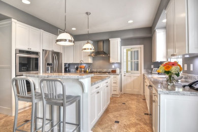 Example of a mid-sized arts and crafts u-shaped travertine floor kitchen pantry design in Orange County with an undermount sink, shaker cabinets, white cabinets, marble countertops, gray backsplash, stone slab backsplash, stainless steel appliances and an island