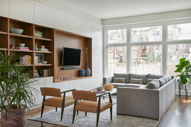 Danish open concept medium tone wood floor family room library photo in Toronto with white walls, no fireplace and a media wall